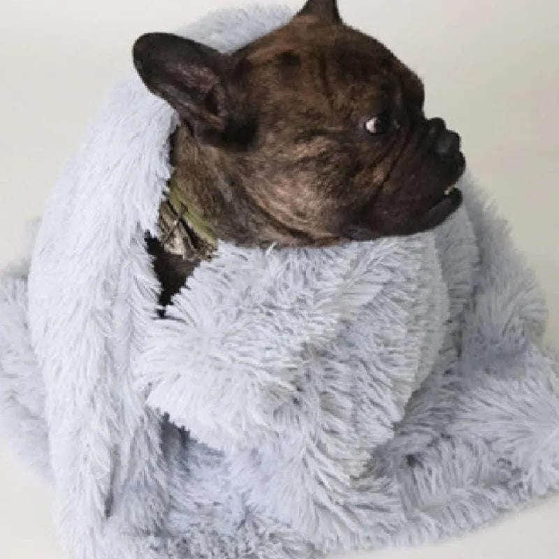 Soft grey plush dog blanket lying flat, showing its size next to a medium-sized dog kennel.