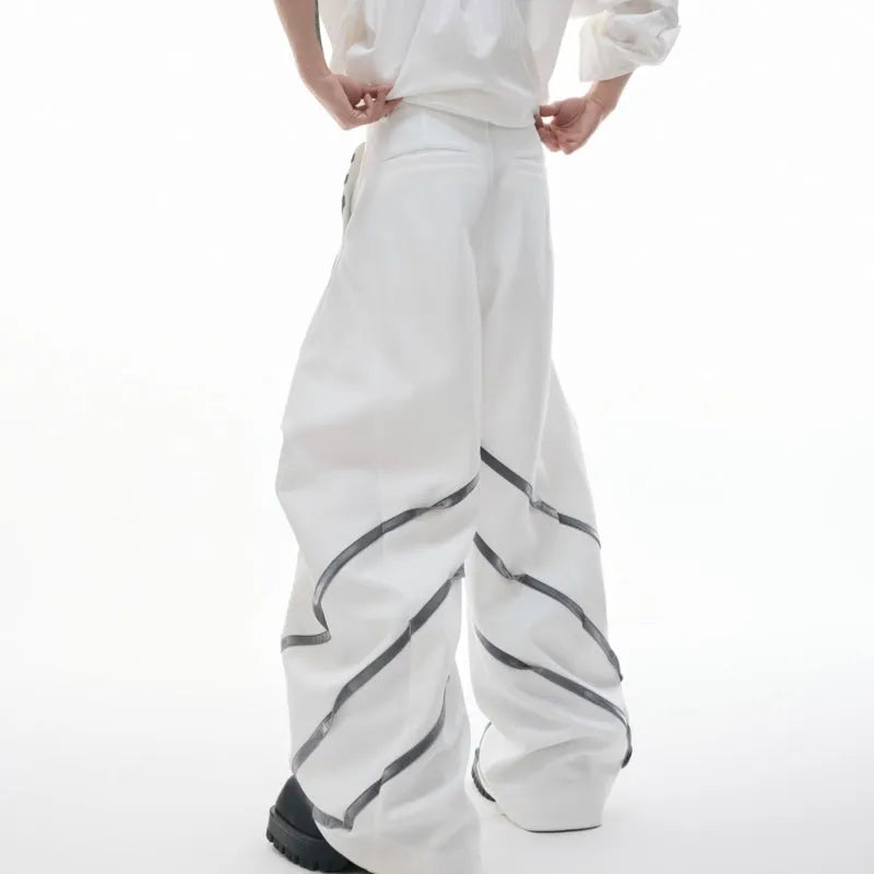 Men's black trousers with three-dimensional cutting, metal striped rivets, and pleated detailing on a hanger.