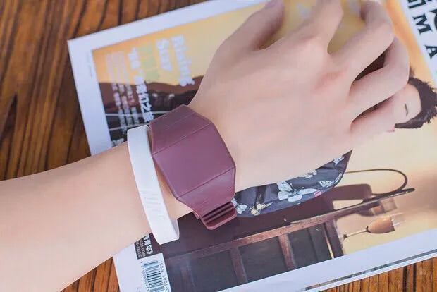 Square white electronic watch with digital display on wrist, showing touch screen and stainless steel buckle
