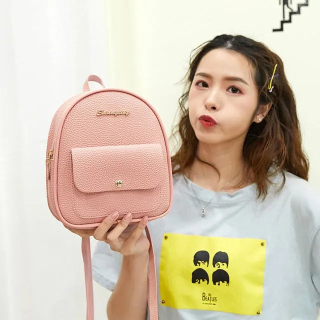 Small black PU leather women's shoulder backpack worn as a backpack, showing zipper closure and compact size.