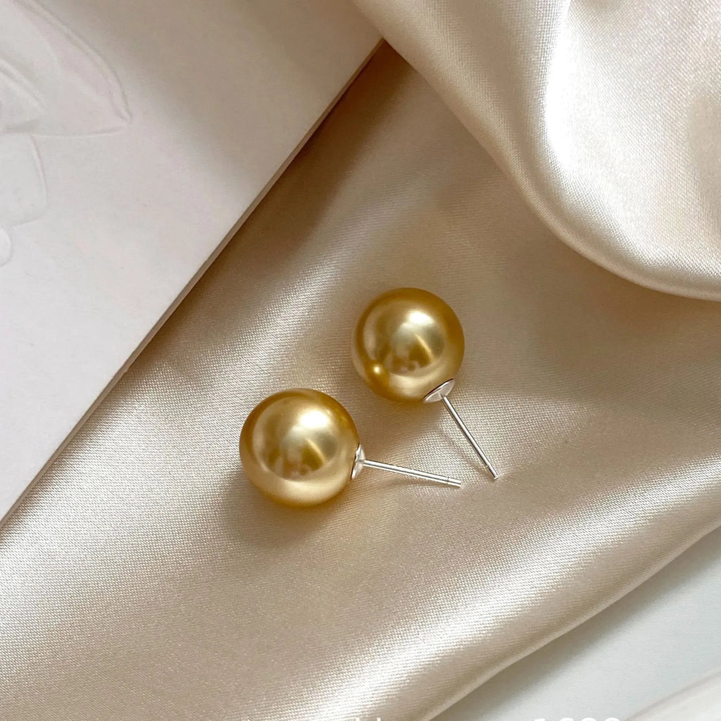 A pair of large geometric pearl stud earrings with an eight-point star detail on a silver setting.
