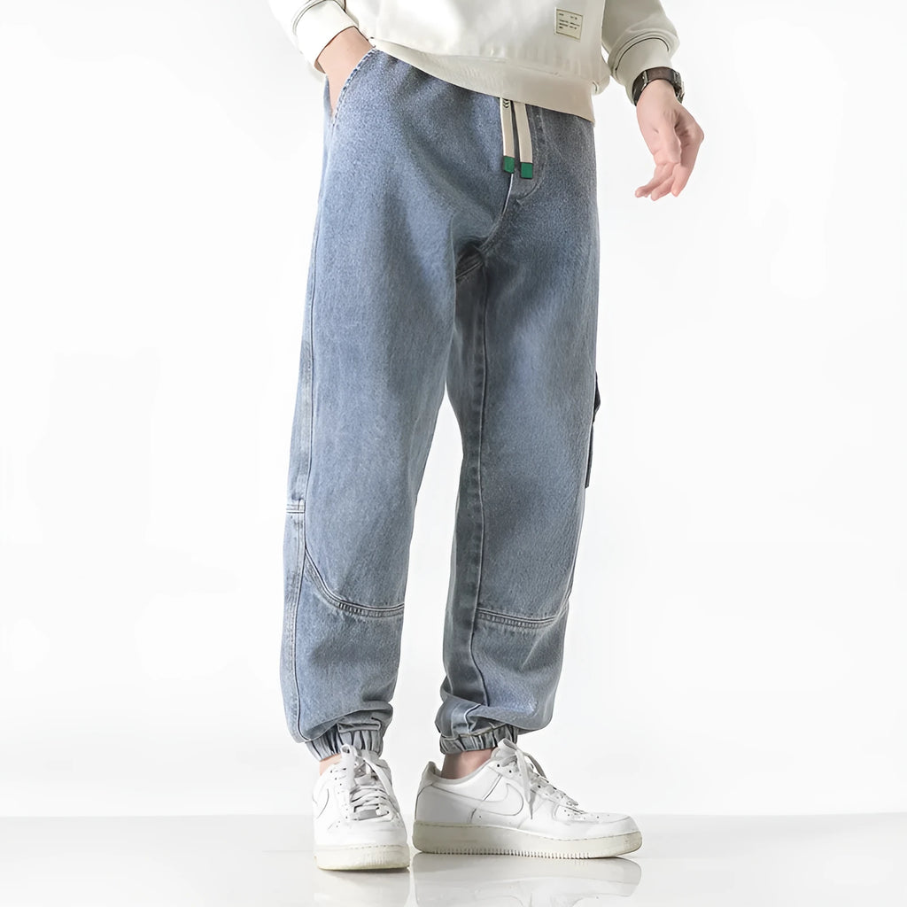 Man wearing grey loose-fit tapered cotton trousers with a mid-rise waist.