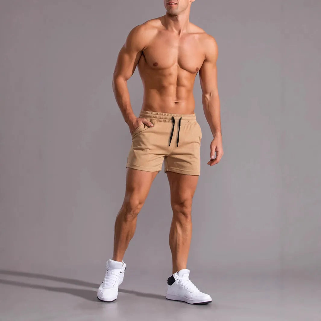 Three pairs of men's solid colour drawstring shorts in black, khaki, and light brown laid flat