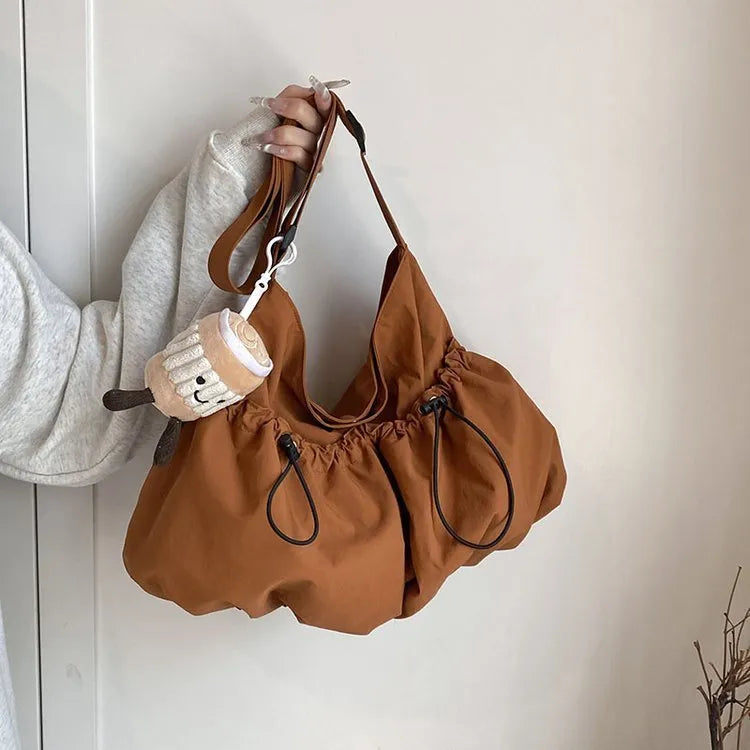 Green ultra-light pleated crossbody cloth bag showing split pocket and foldable design.