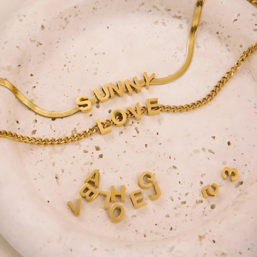 Gold electroplated titanium steel necklace with a letter A charm on a grinding chain.