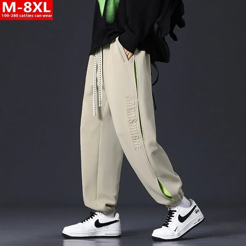 Man wearing grey green loose-fit cotton trousers with stitching print detail and an ankle band.