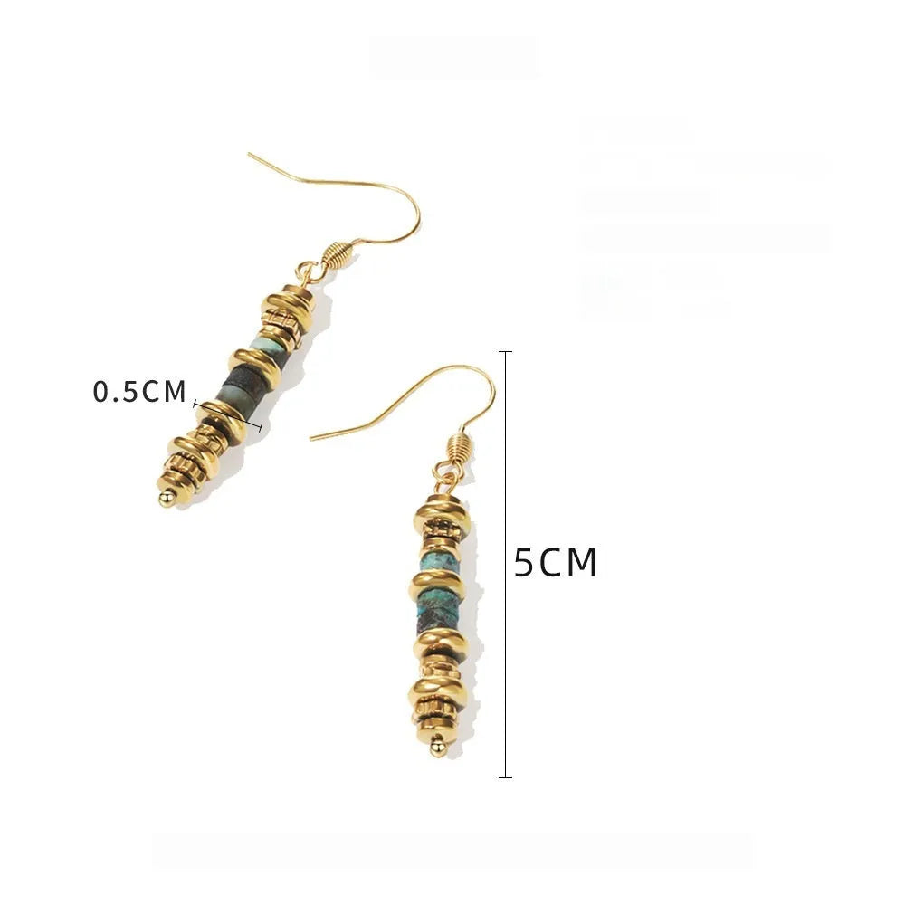 A pair of geometric-shaped, gold-toned dangle earrings on a plain background.
