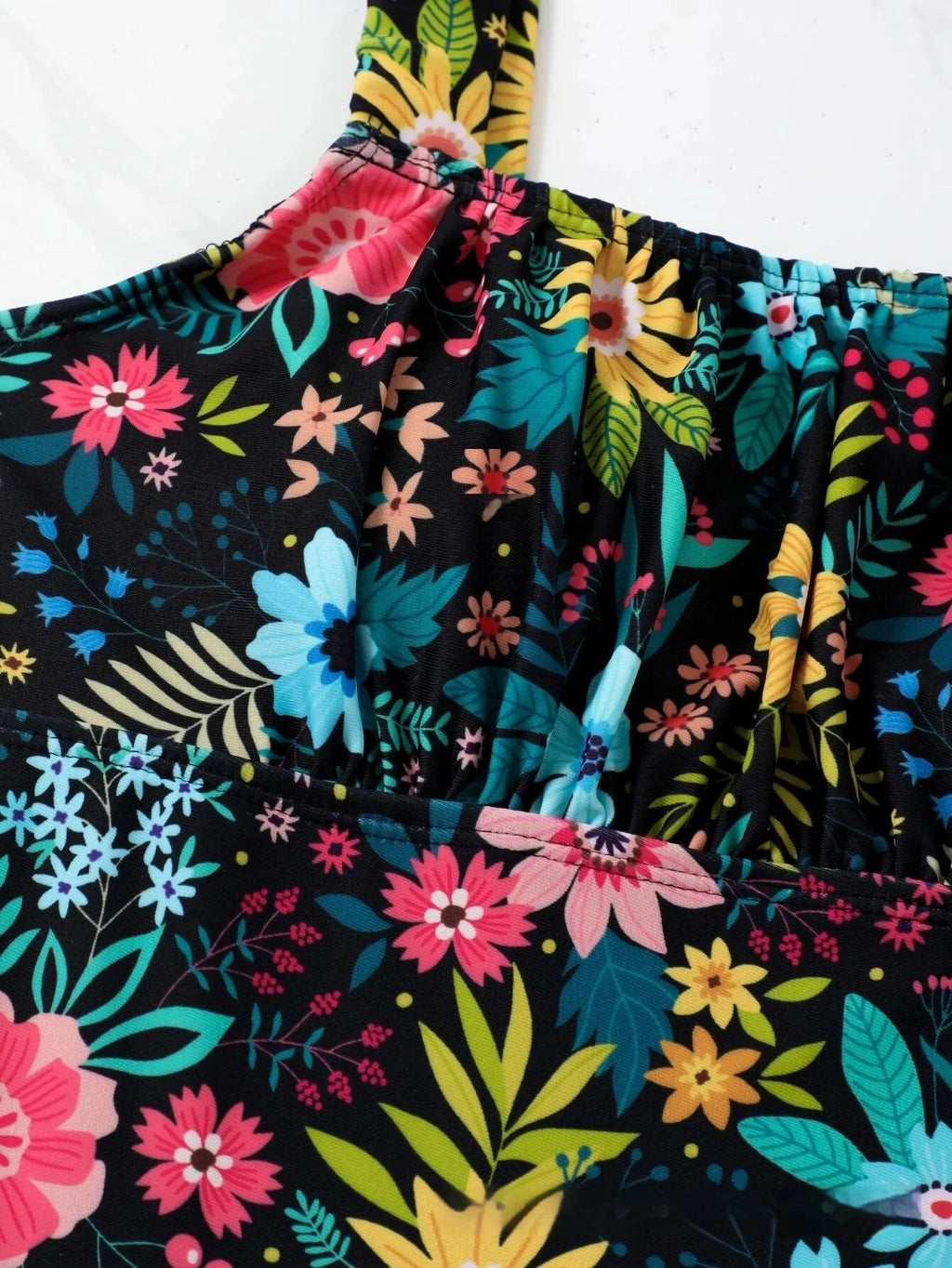 Women's one-piece swimsuit with blue floral print on black background, showing front and back views.