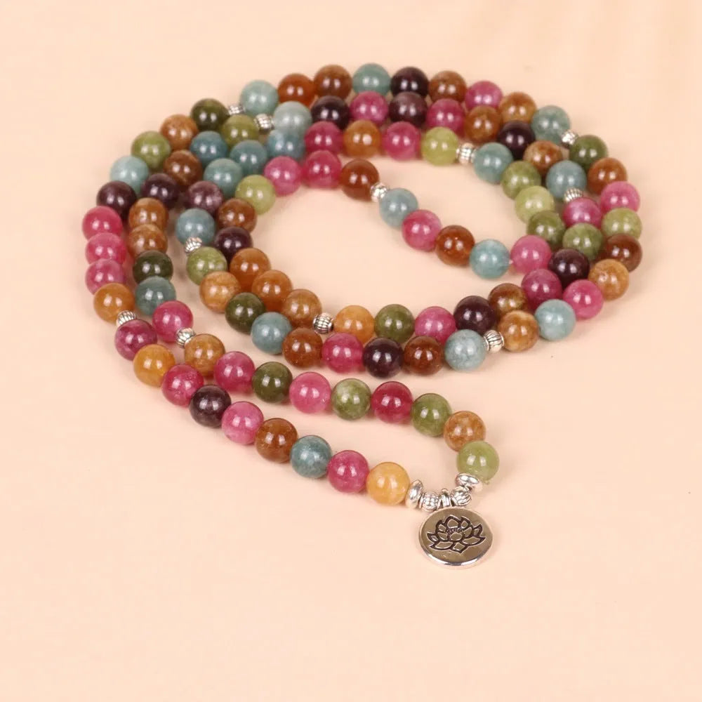 Close-up of a multi-layer beaded bracelet with 108 beads and a hanging lotus charm, made from alloy and tourmaline-coloured material.