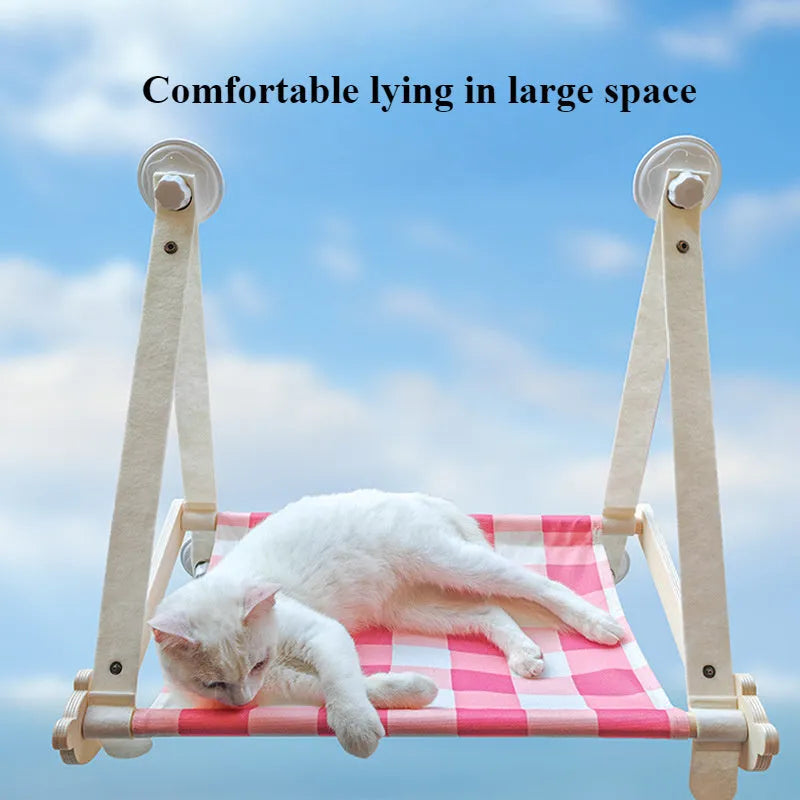 Wooden frame cat hammock with linen mat attached to a window via suction cups, shown in pink colour.
