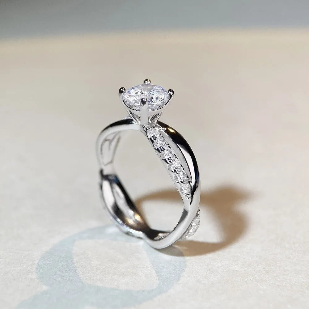 Geometric cross design moissanite ring with twisted sterling silver band and four-claw setting.