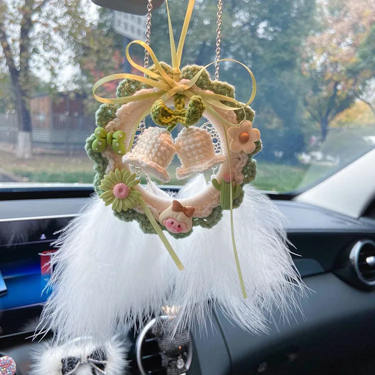 Handwoven wool bell orchid flower car pendant on a green background.