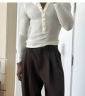 Man wearing a cream-coloured ribbed long-sleeve Henley top with a buttoned neckline.