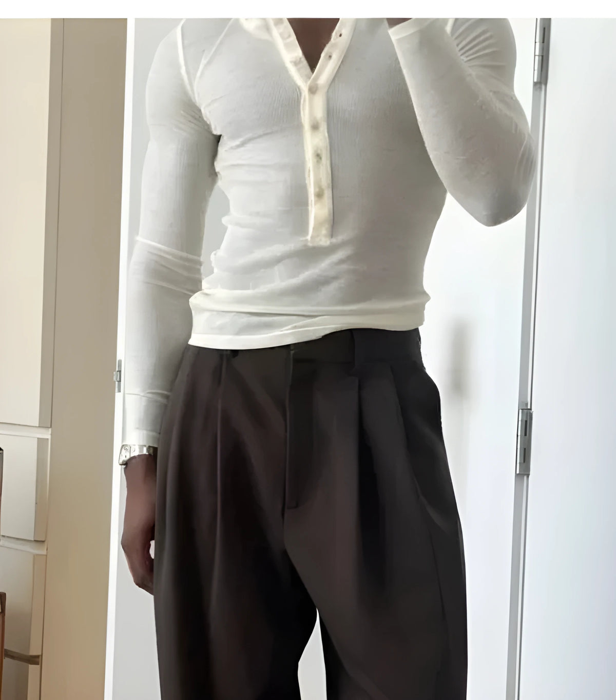 Man wearing a cream-coloured ribbed long-sleeve Henley top with a buttoned neckline.
