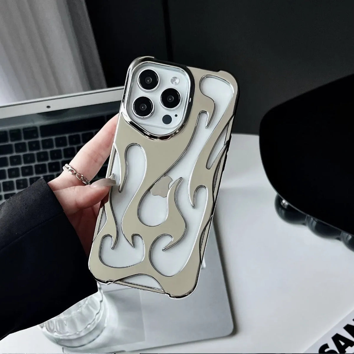 Electroplated hollow flame pattern iPhone case in silver TPU soft shell on a mobile phone.