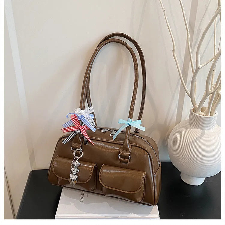 Women's black PU leather retro pillow handbag with double shoulder straps shown carried underarm