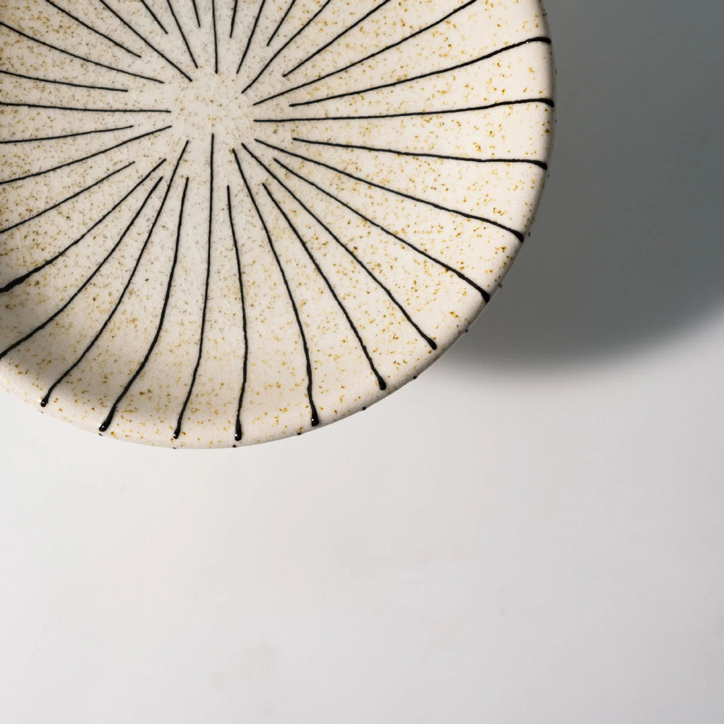 Black and white striped synthetic resin dessert plate on a table.