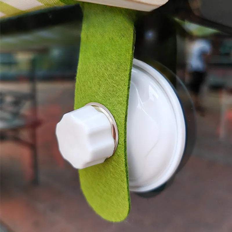 Wooden frame cat hammock with linen mat attached to a window via suction cups, shown in pink colour.