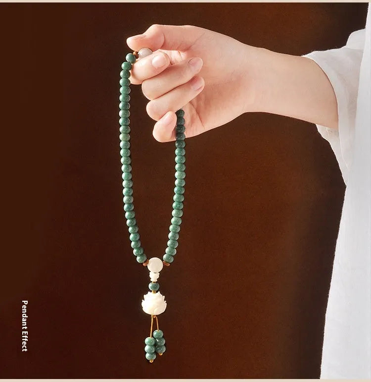 White and green beaded bracelet with a double ring safety buckle and a prominent double ring lotus bead decoration.