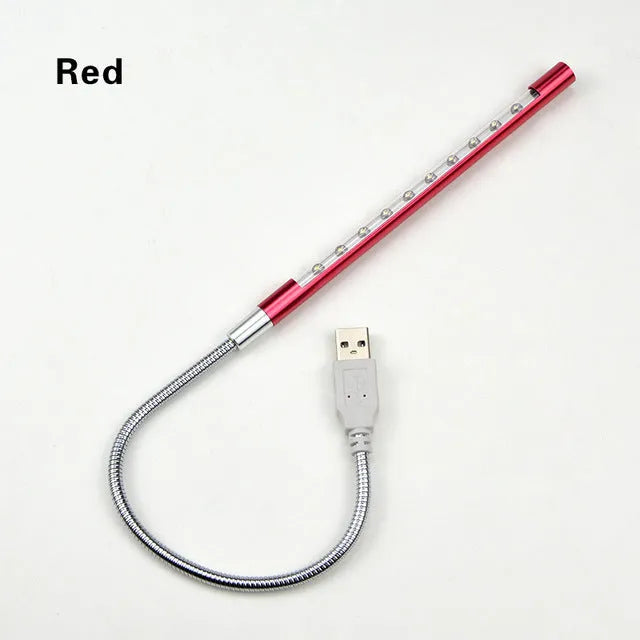 Slender silver spiral USB LED night light on a wooden desk next to a laptop.
