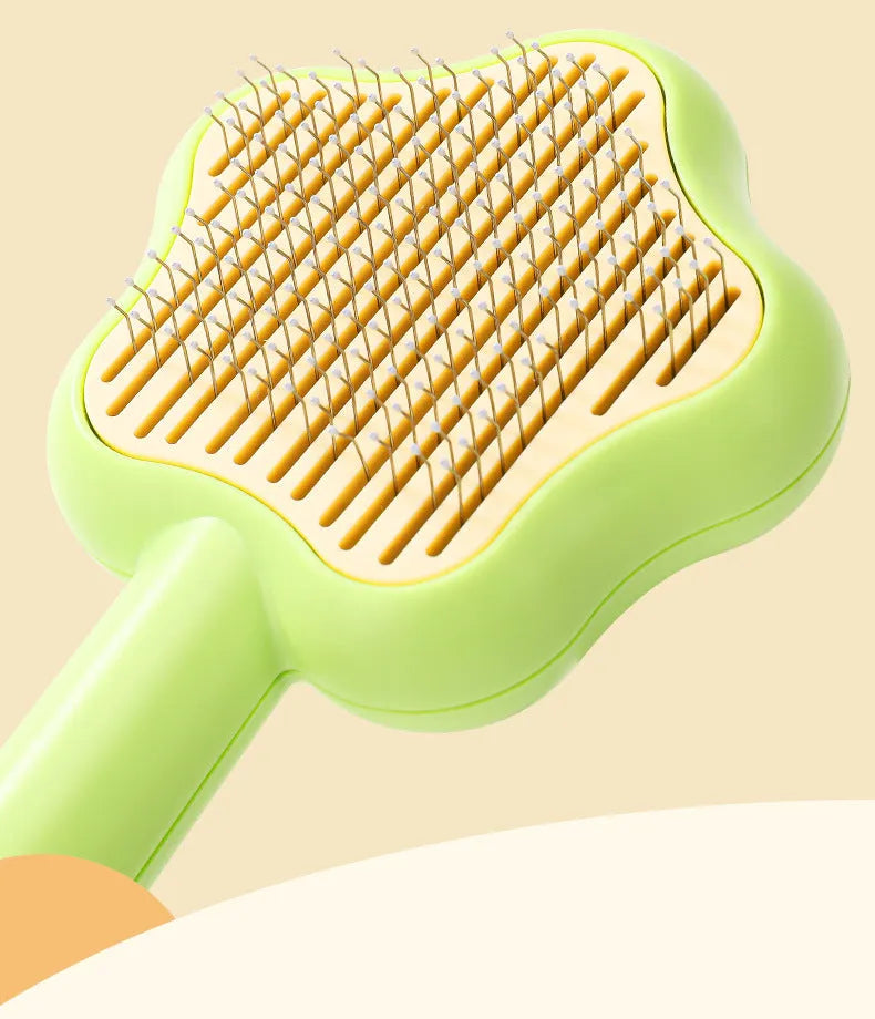 Green self-cleaning cat comb with stainless steel pins on a white background