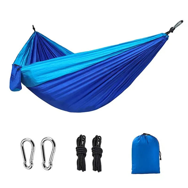Blue nylon parachute cloth camping hammock hung between two trees.