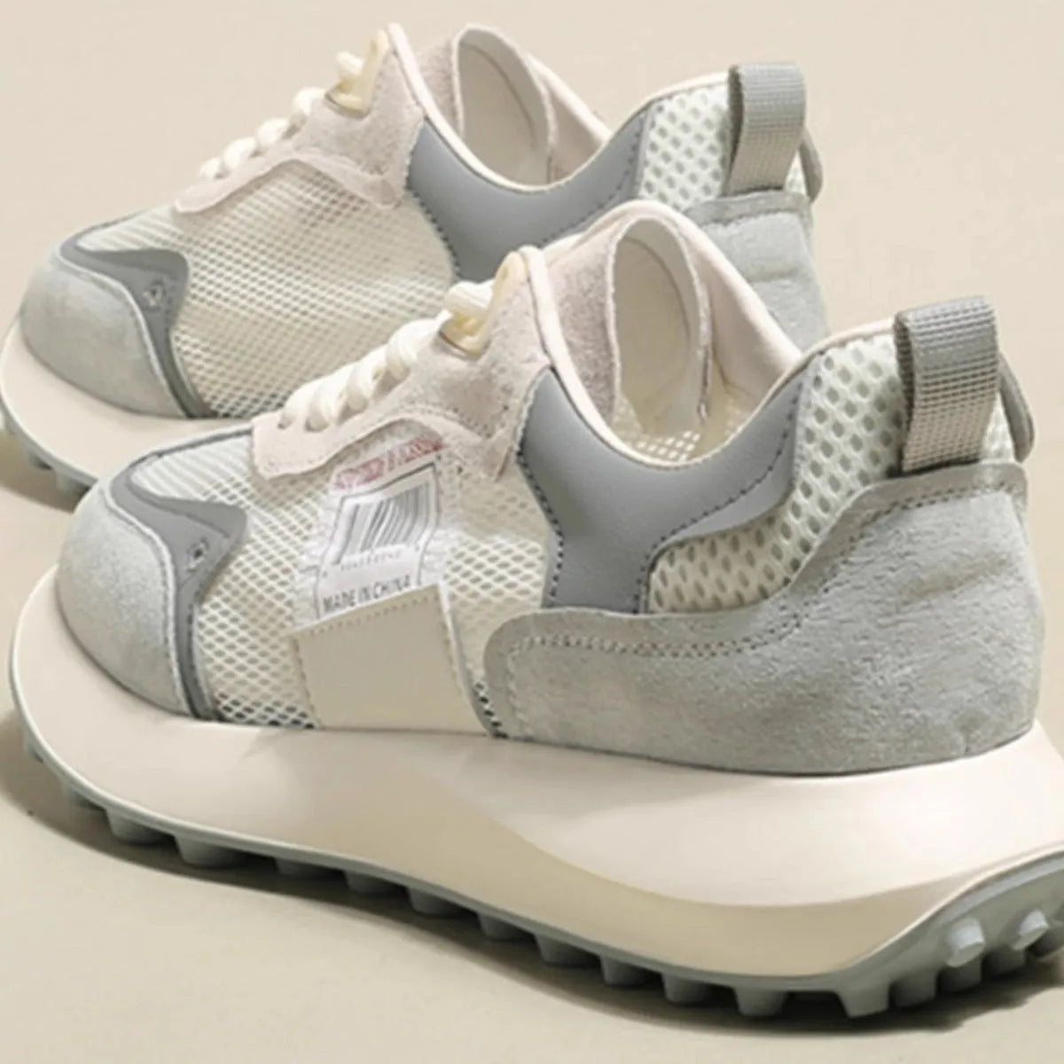 Grey and pink women's low-top retro sneaker with round toe and rubber sole on a white background.