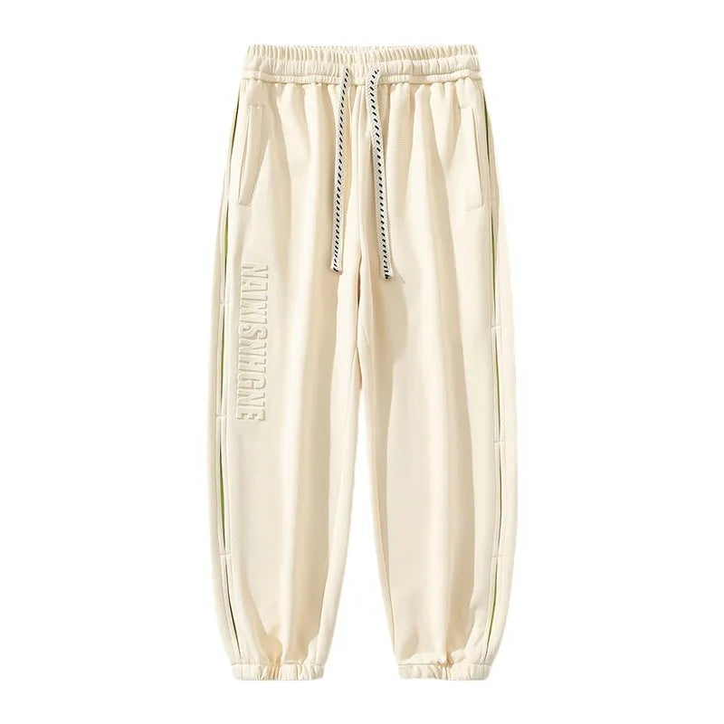 Man wearing grey green loose-fit cotton trousers with stitching print detail and an ankle band.