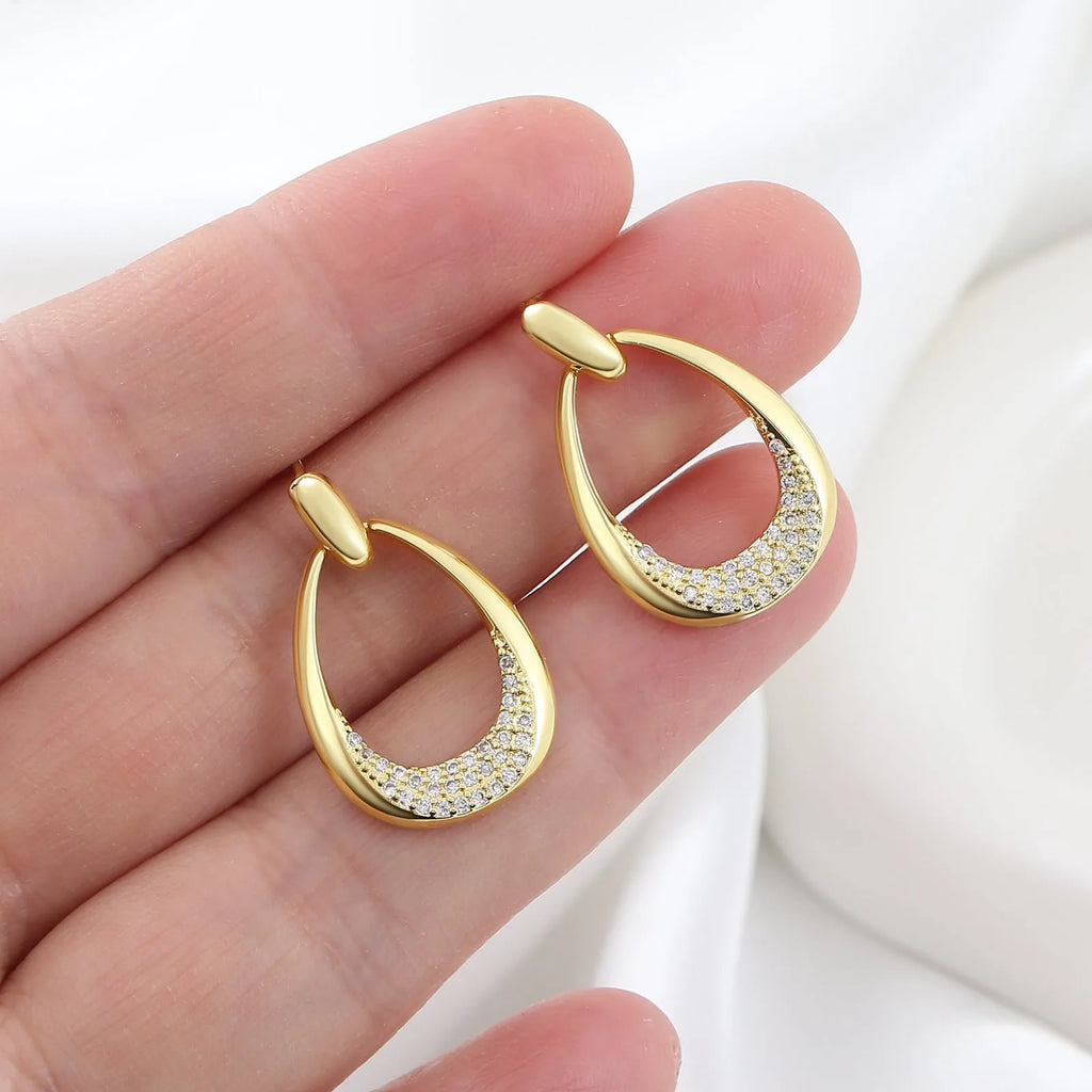 Yellow gold geometric drop earrings with round and oval ring elements on white background