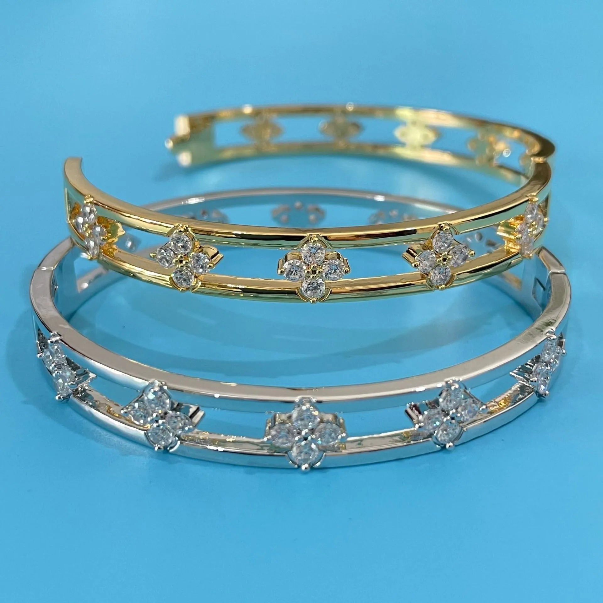 Gold and silver hollow women's bracelets with four-leaf clover zircon charms on a white background.