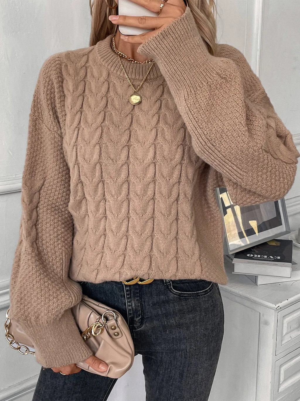 Women's beige loose-fitting sweater with twisted detailing on a hanger.