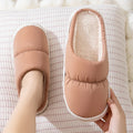 Blue down cotton slippers with artificial leather upper, thick rubber sole, and plush lining shown on a wooden floor.
