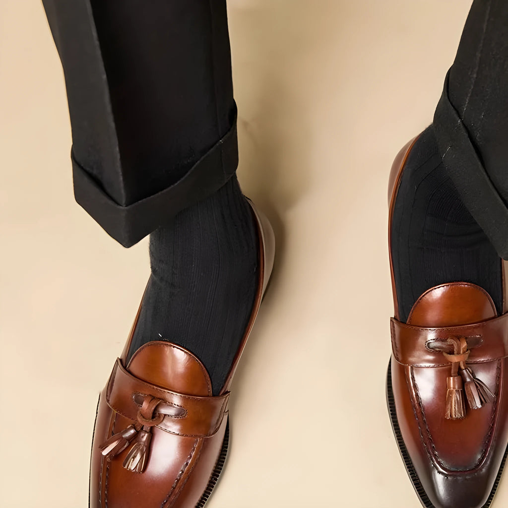 Men's black leather tassel loafers with rubber sole shown from side view
