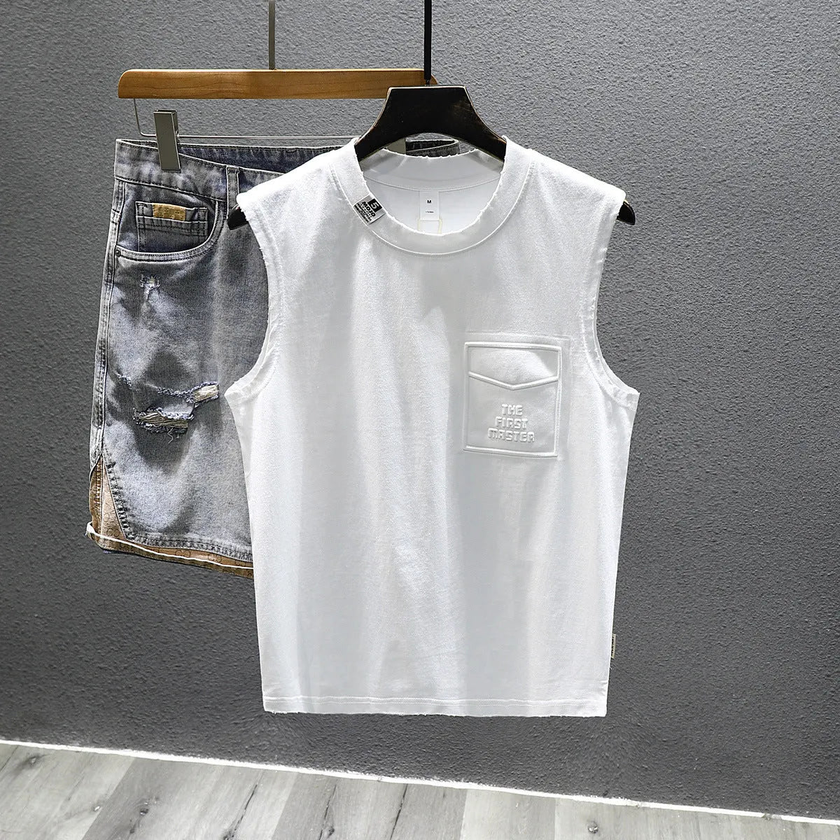Loose fit cotton sleeveless t-shirt in black on a hanger, showing straight hem design.