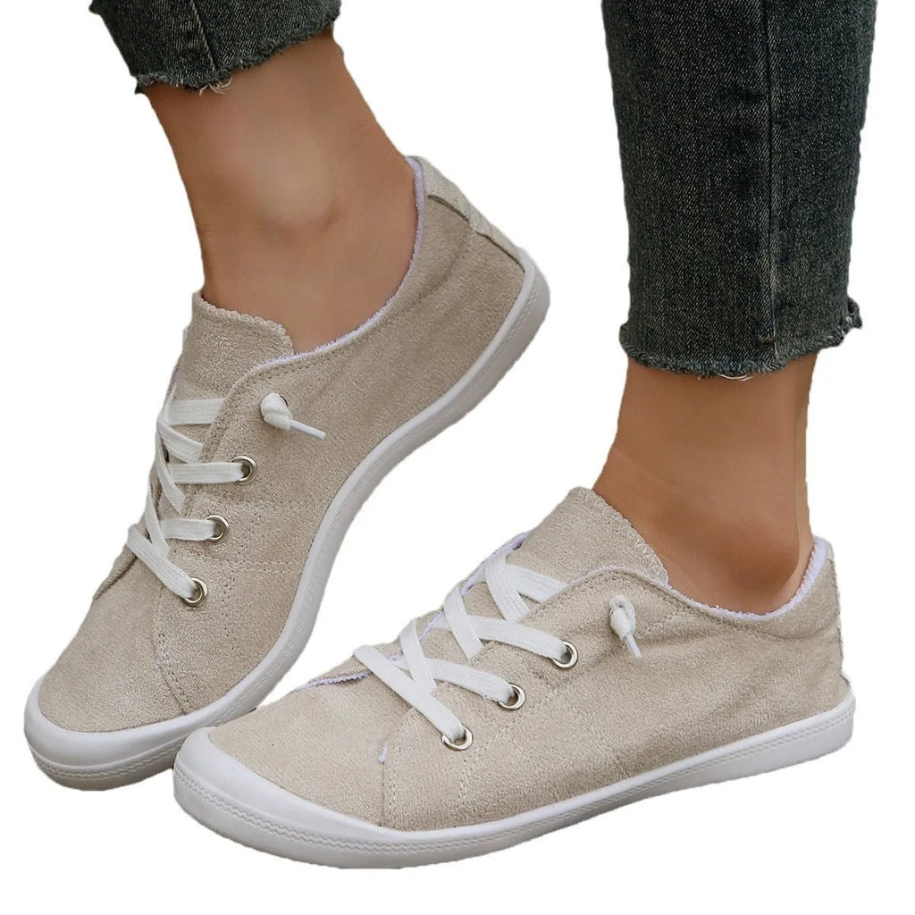 Women's creamy-white low-top fabric sneakers with a rubber sole on a neutral background.