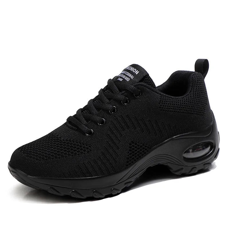Women's black mesh sneakers with round toe, front lace-up closure, and mid heel on grey background