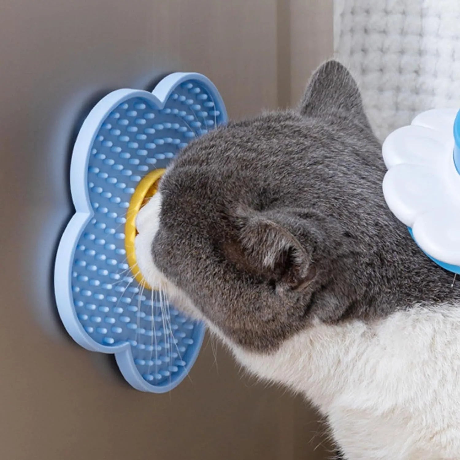 Flower-shaped silicone pet licking mat in blue with suction cups on the back, shown on a tiled surface.