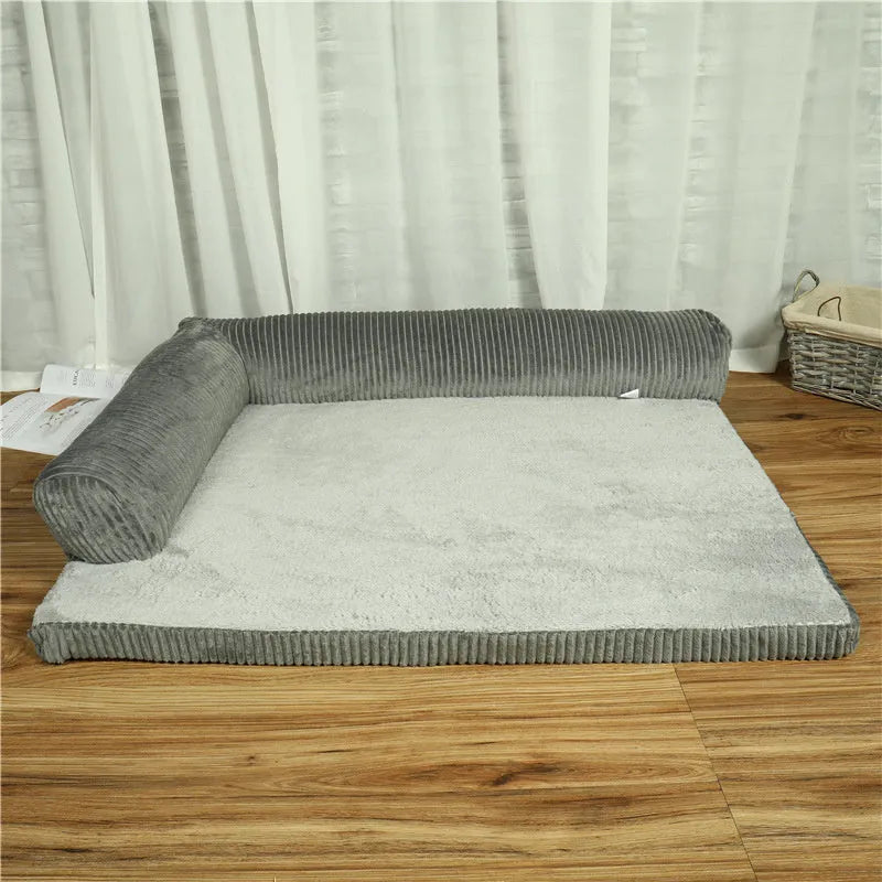 Corduroy pet sofa dog bed with a raised bolster, shown in a grey colour on a wooden floor.