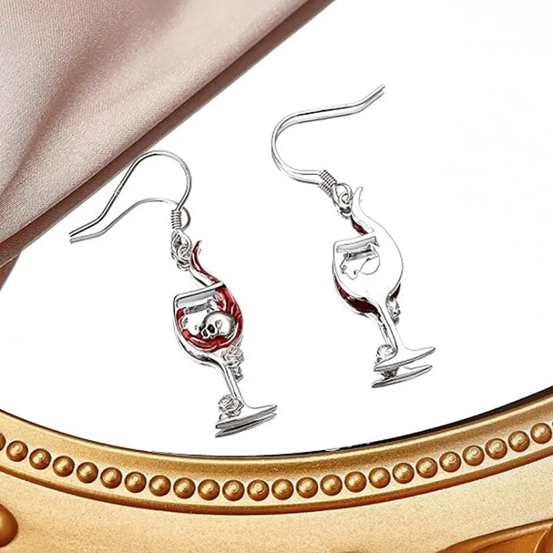 A pair of silver-toned zinc alloy earrings shaped like wine glasses adorned with skull details, on a plain background.