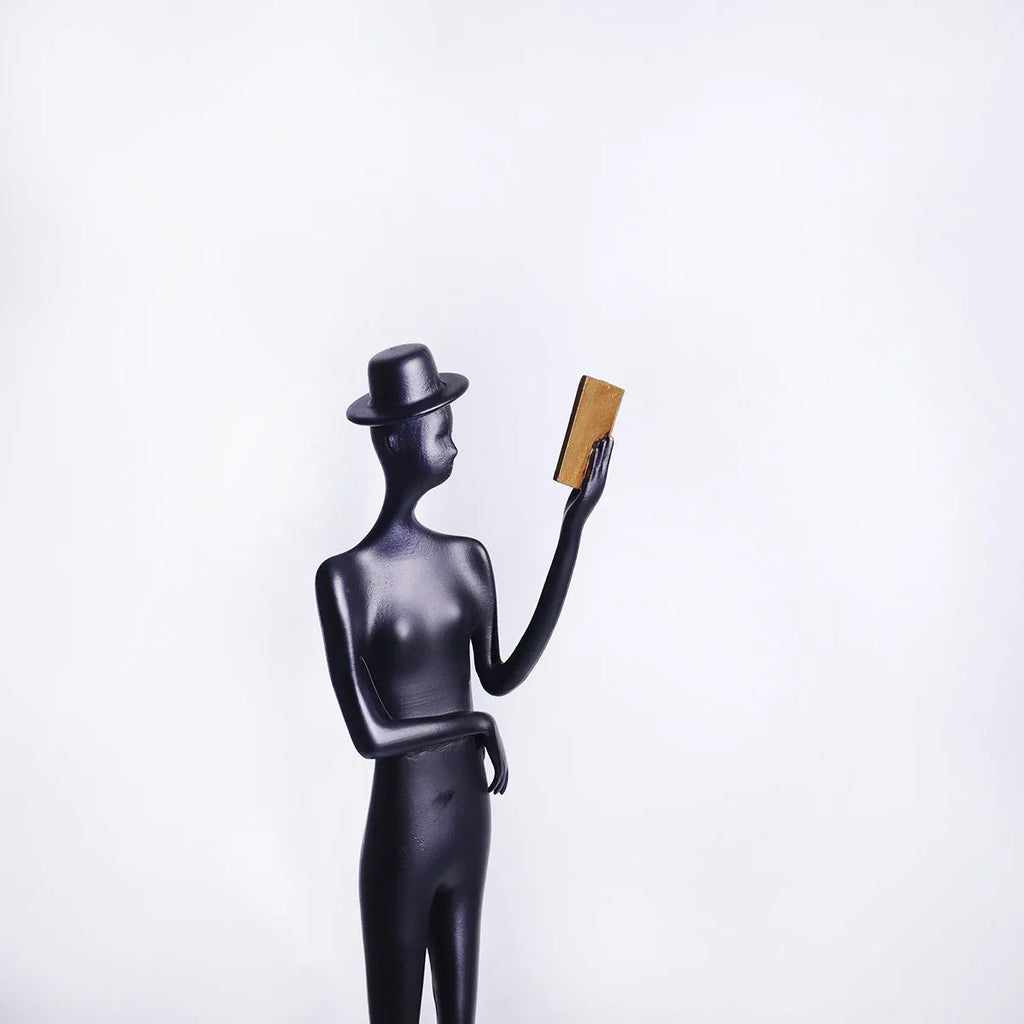 Black cast aluminium desktop sculpture of reading woman figure measuring 12x51cm in modern minimalist style.