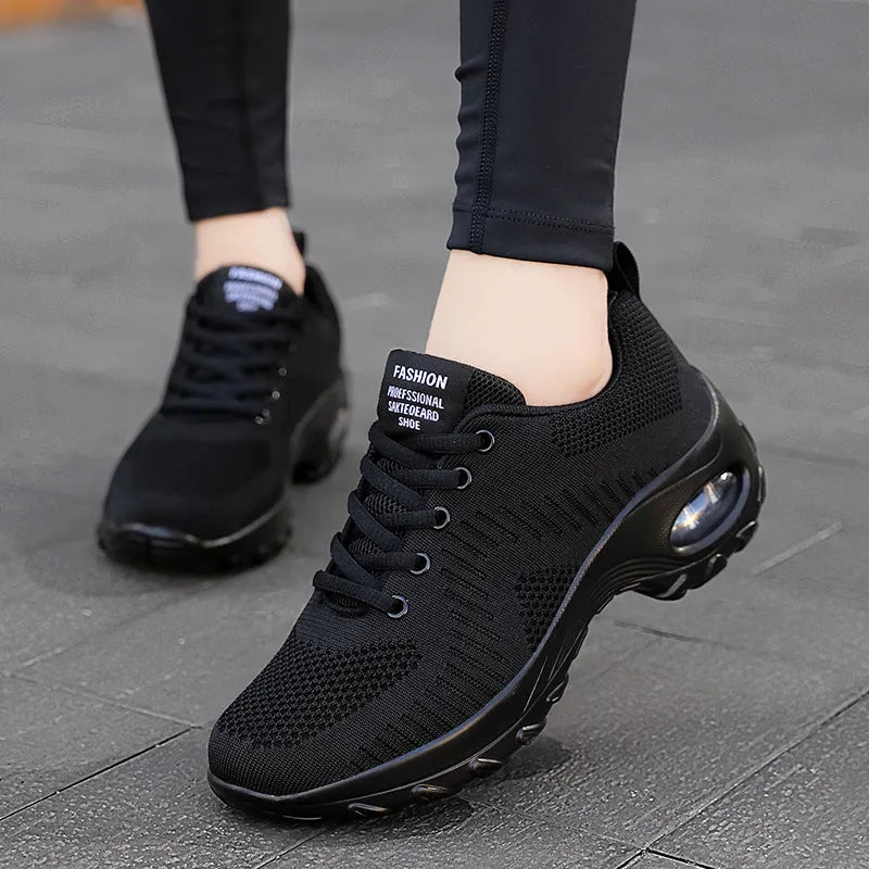 Women's black mesh sneakers with round toe, front lace-up closure, and mid heel on grey background
