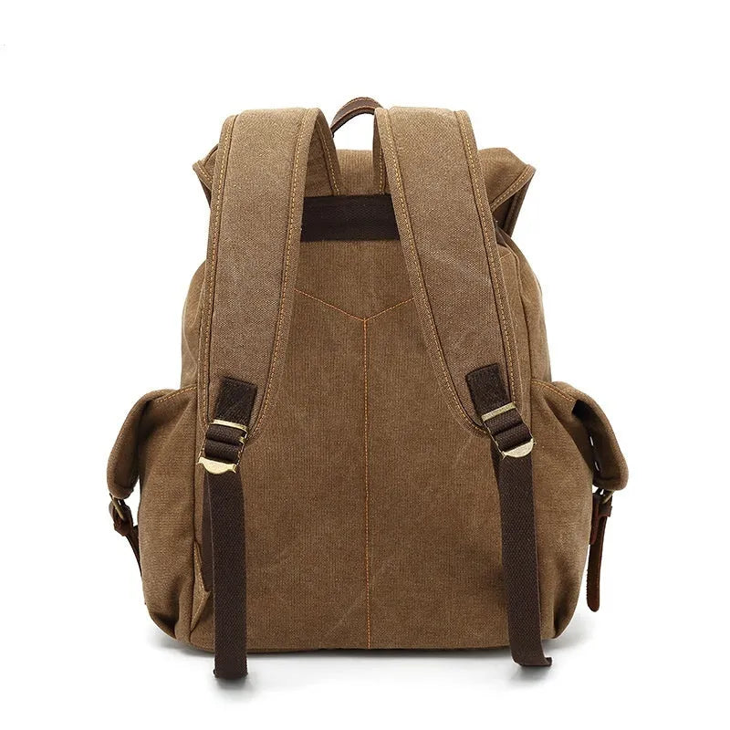 Retro canvas backpack in military green with antique bronze hardware, shown next to a 16-inch laptop.
