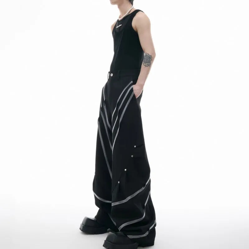 Men's black trousers with three-dimensional cutting, metal striped rivets, and pleated detailing on a hanger.