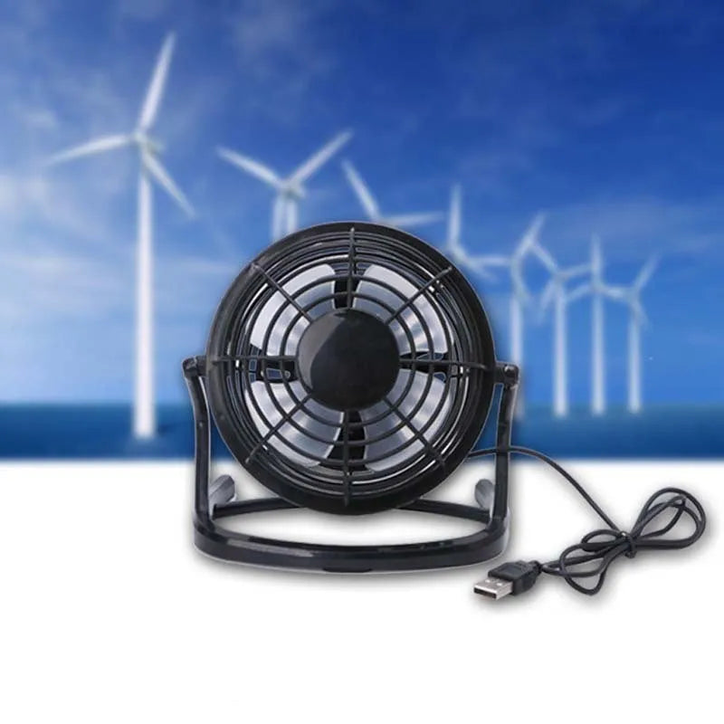 Mini black USB desk fan with adjustable angle on wooden desk next to laptop