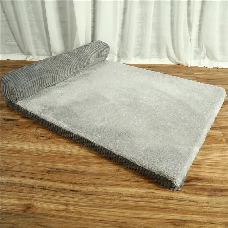 Corduroy pet sofa dog bed with a raised bolster, shown in a grey colour on a wooden floor.