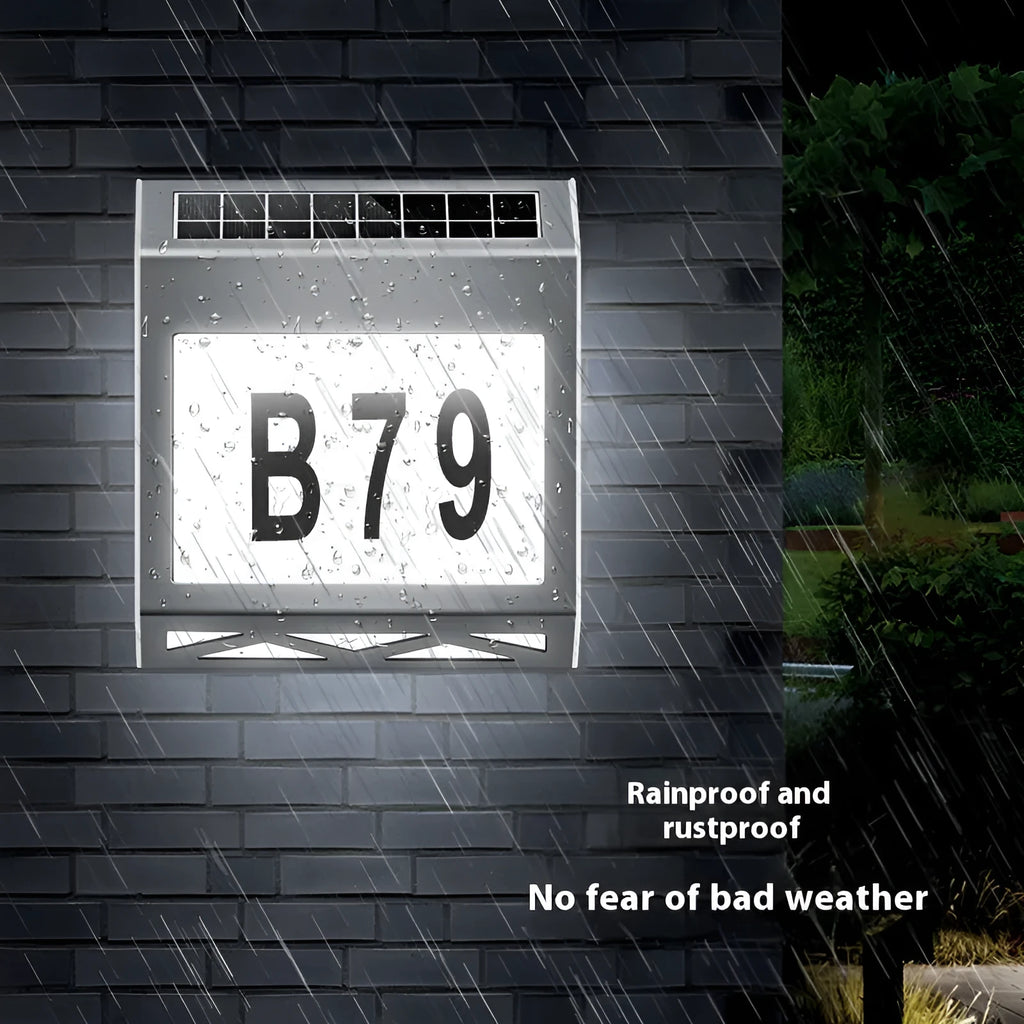 Black solar powered doorplate light with digital LED display mounted on brick wall