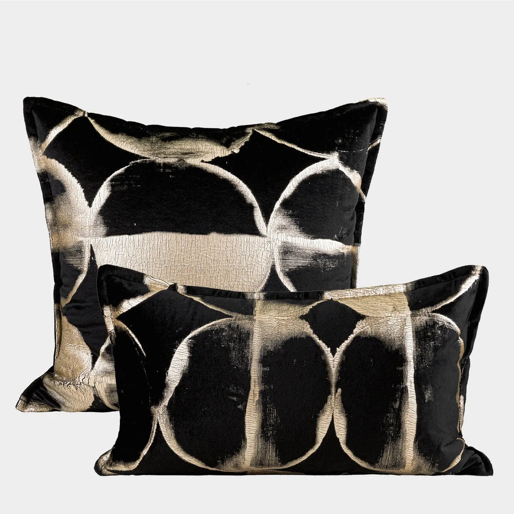 Black and gold abstract pattern decorative flannel pillow with removable cover on a grey sofa.