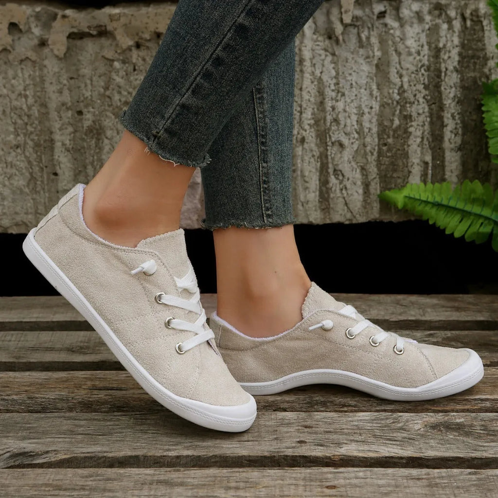 Women's creamy-white low-top fabric sneakers with a rubber sole on a neutral background.