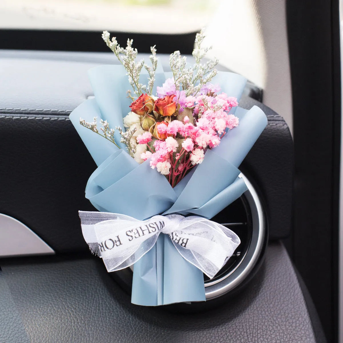 Handmade dried flower car air freshener ornament clipped to a car vent, showing colour and natural material detail.