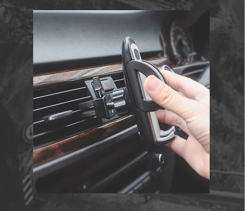Black plastic mobile phone holder clipped to a car air conditioning vent.